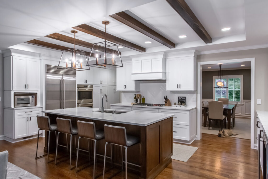 Kitchen remodel with white cabinetry, dark island, and exposed wood beam ceiling